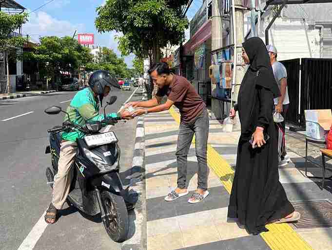 Anggota Komite Ekraf Bojonegoro membagikan nasi bungkus kepada pengemudi ojek online dalam kegiatan Jumat Berkah di depan Bojonegoro Creative Hub