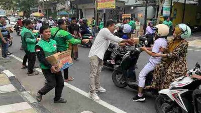 Suwito Ketua Komunitas Ojol Bojonegoro membagikan takjil kepada pengendara di Jalan Pemuda saat Ramadhan