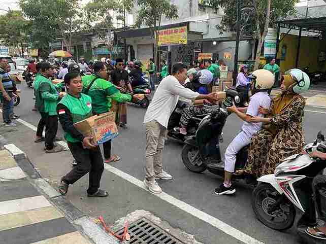 Suwito Ketua Komunitas Ojol Bojonegoro membagikan takjil kepada pengendara di Jalan Pemuda saat Ramadhan