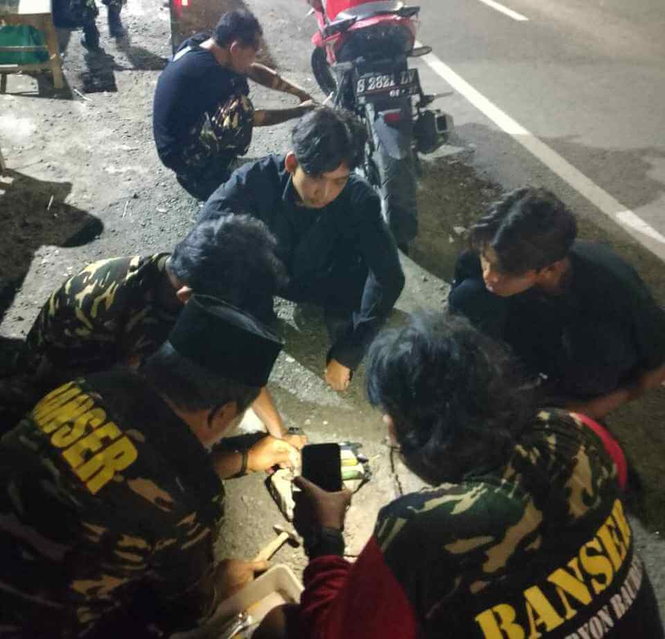 Banser Baureno dan Balen memperbaiki motor pemudik di posko mudik dini hari