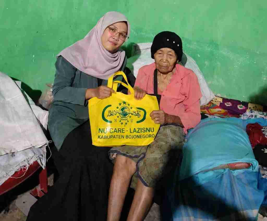 Relawan LAZISNU Bojonegoro bersama IPNU-IPPNU menyerahkan bantuan zakat fitrah kepada warga penerima di rumah sederhana