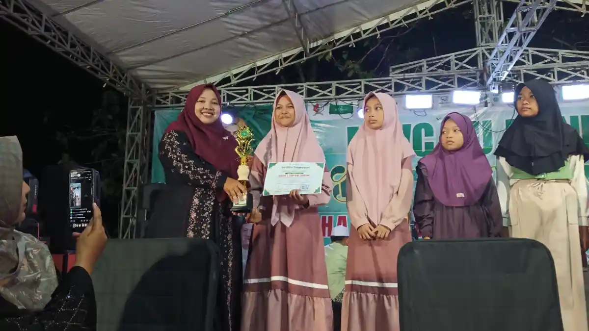 Shofia Aina Lathifa menerima trofi dan piagam Juara 1 Tartilul Qur’an dari Sekcam Dander pada Gebyar Sholawat MWCNU Dander 2026